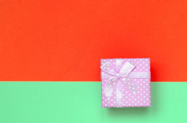 Pequeña caja de regalo rosa se encuentran en el fondo de textura de la moda pastel de color turquesa y rojo papel de colores — Foto de Stock