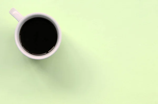 Piccola tazza di caffè bianco su sfondo texture di carta di colore calce pastello moda — Foto Stock
