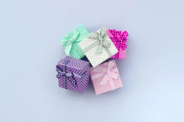 带丝带的小彩色礼品盒堆放在紫罗兰色背景上 — 图库照片
