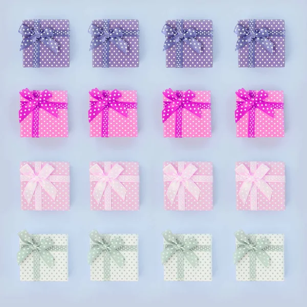 Montones de pequeñas cajas de regalo de colores con cintas se encuentra sobre un fondo violeta — Foto de Stock