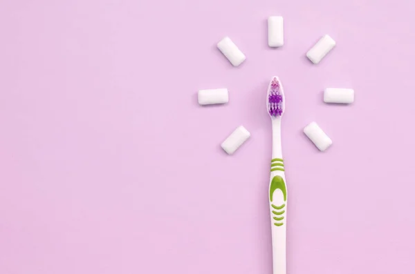 Zahnbürste und Kaugummis liegen auf pastellrosa Hintergrund — Stockfoto