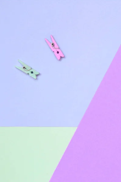 Due picchetti di legno colorati si trovano su sfondo texture di moda viola pastello, turchese e rosa colori carta — Foto Stock