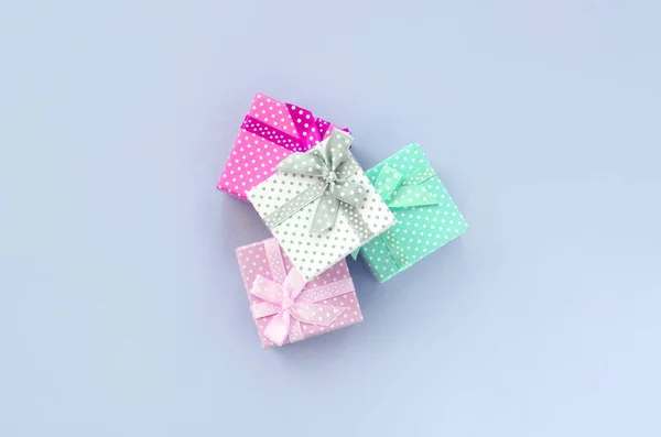 Halom egy kis színes ajándékdoboz szalagok fekszik a lila háttér — Stock Fotó
