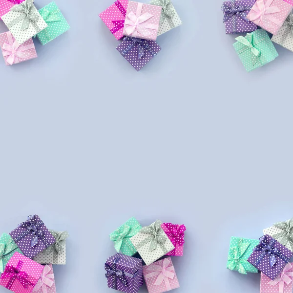 Stapel kleiner farbiger Geschenkboxen mit Schleifen liegen auf violettem Hintergrund — Stockfoto