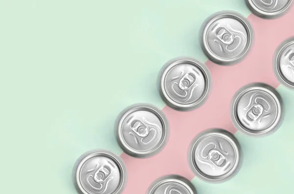 Many metallic beer cans on texture background of fashion pastel turquoise and pink colors