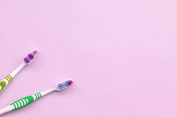 Dwie szczoteczki do zębów leżą na pastelowych różowym tle — Zdjęcie stockowe
