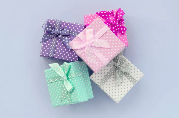 Pile of a small colored gift boxes with ribbons lies on a violet background — Stock Photo, Image