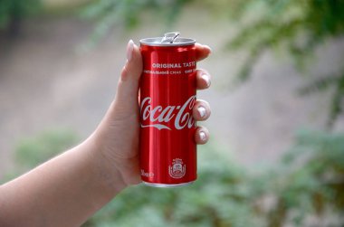 Beyaz kadın kırmızı Coca-Cola kalay yeşil bahçe arka plan ile tutar