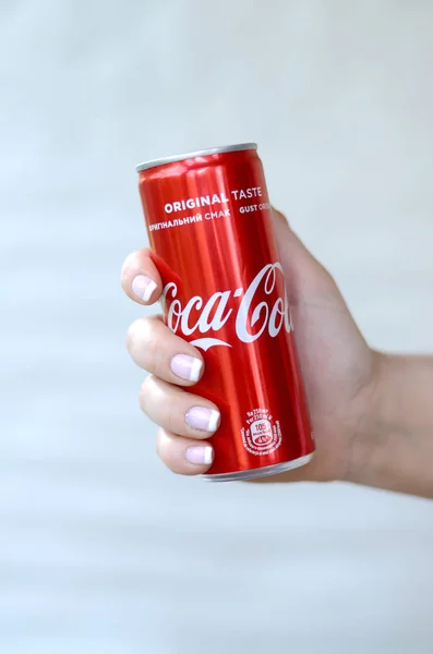 La mano femenina sostiene la lata de Coca-Cola roja sobre fondo de pared blanco — Foto de Stock