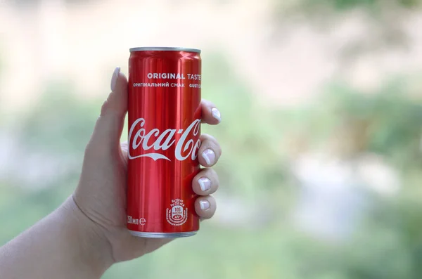 Mulher caucasiana detém lata de Coca-Cola vermelha com fundo verde jardim — Fotografia de Stock