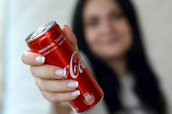 Счастливая женщина держит безалкогольную банку из-под алюминия Coca-Cola в гараже — стоковое фото