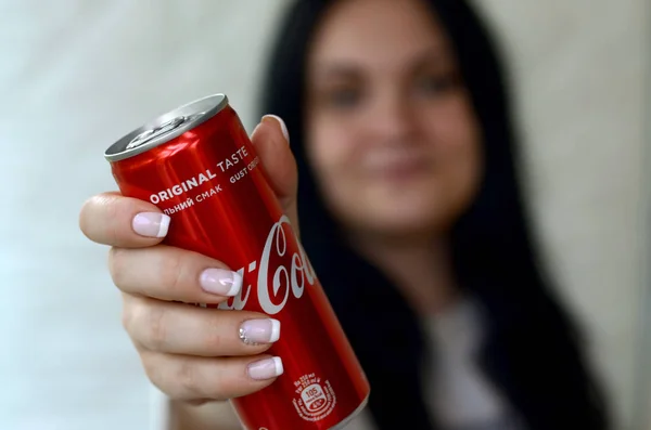 Счастливая женщина держит безалкогольную банку из-под алюминия Coca-Cola в гараже — стоковое фото