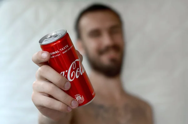 Glimlachende man geeft niet-alcoholische Coca-Cola aluminium tin kan in garage interieur — Stockfoto