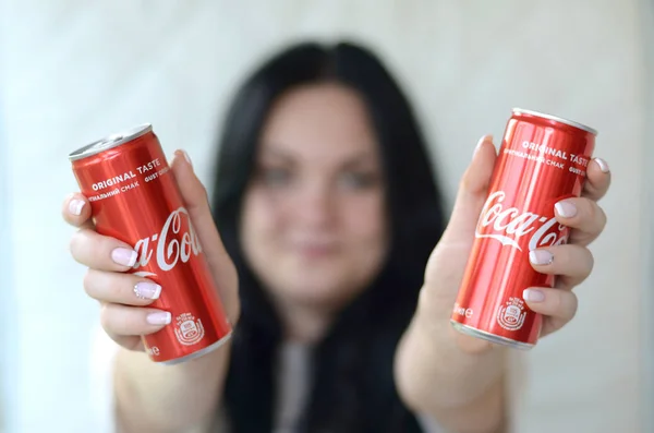Donna felice in possesso di due lattine di alluminio Coca-Cola analcoliche in garage interno — Foto Stock