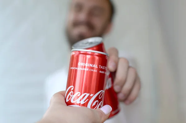 Happy young man raise Coca-Cola tin can with female friend in garage interior — Stock Photo, Image