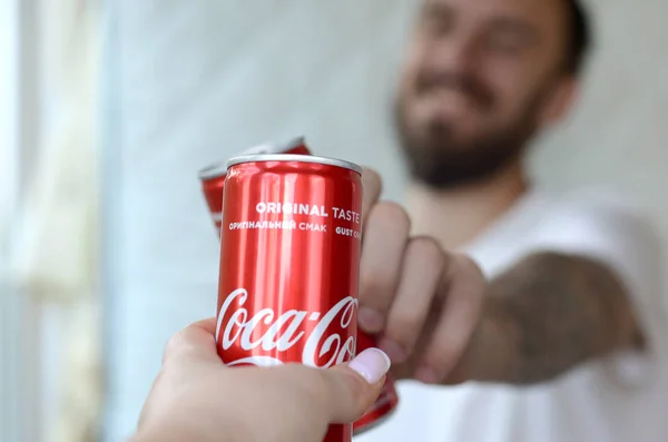 Jovem feliz levantar lata Coca-Cola com amigo feminino no interior garagem — Fotografia de Stock