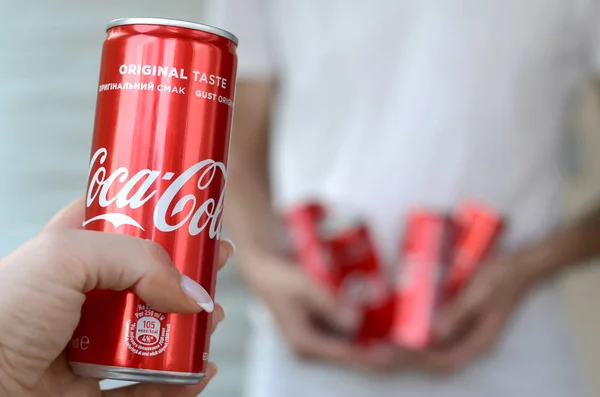 Manos masculinas sostiene algunas latas de Coca-Cola en el interior del garaje y mano femenina con una lata en primer plano —  Fotos de Stock