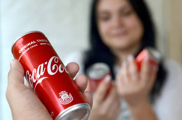 Gelukkige vrouw met weinig Coca-Cola tin blikjes in garage interieur en mannelijke hand met een kan op de voorgrond — Stockfoto