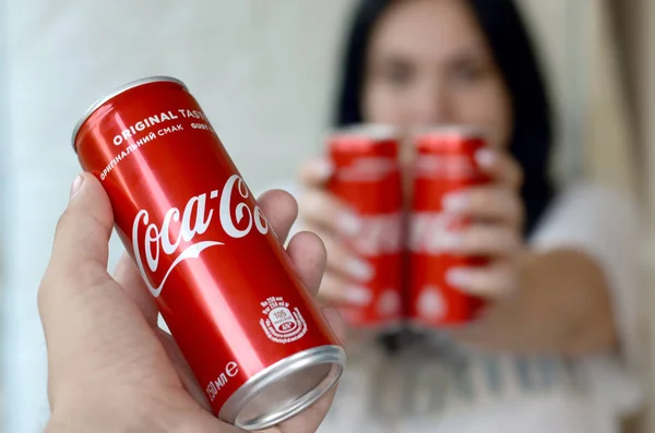 Gelukkige vrouw met weinig Coca-Cola tin blikjes in garage interieur en mannelijke hand met een kan op de voorgrond — Stockfoto