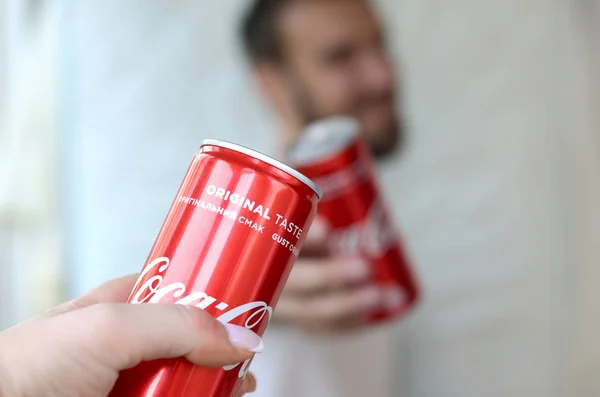 Lycklig ung man höja Coca-Cola Tin kan med kvinnlig vän i garage inredning — Stockfoto