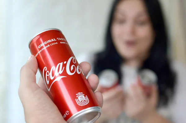 Donna felice che tiene poche lattine Coca-Cola in garage interno e mano maschile con una lattina in primo piano — Foto Stock