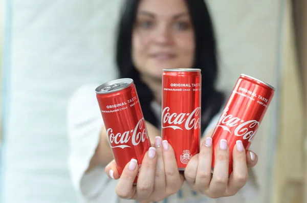 Donna felice che tiene molte lattine di alluminio Coca-Cola analcoliche in garage interno — Foto Stock