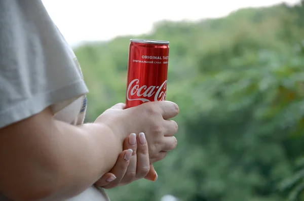 Mulher caucasiana detém lata de Coca-Cola vermelha com fundo verde jardim — Fotografia de Stock