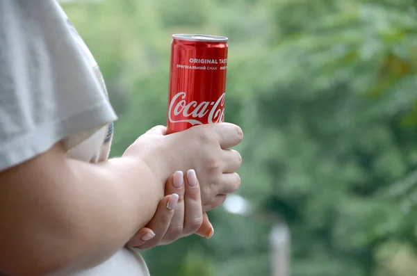 Femme caucasienne tient boîte de Coca-Cola rouge avec fond de jardin vert — Photo