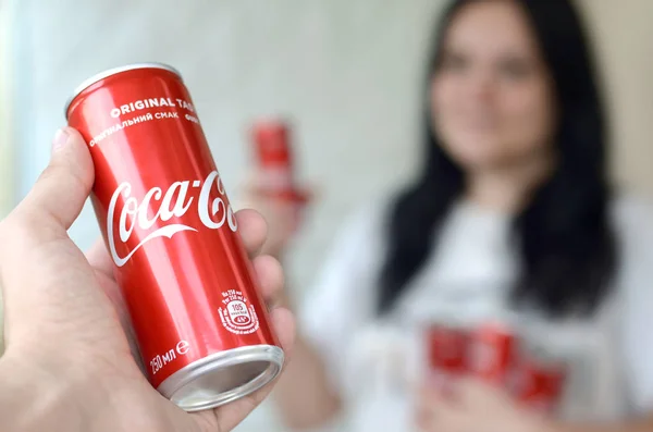 Gelukkige vrouw met weinig Coca-Cola tin blikjes in garage interieur en mannelijke hand met een kan op de voorgrond — Stockfoto