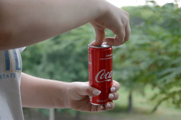 Blanke vrouw houdt rode Coca-Cola tin kan met groene tuin achtergrond — Stockfoto