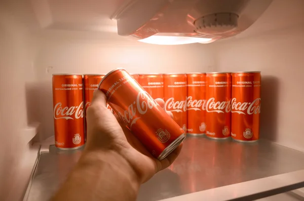 男性の手は、コカコーラの赤い飲み物は、コーラ缶の完全な国内のクーラー冷蔵庫の中にすることができます — ストック写真