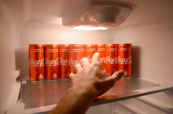 Mão masculina quer pegar Coca-cola lata de bebida vermelha dentro refrigerador doméstico geladeira cheia de latas de coca-cola — Fotografia de Stock