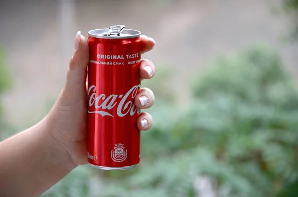 Mulher caucasiana detém lata de Coca-Cola vermelha com fundo verde jardim — Fotografia de Stock