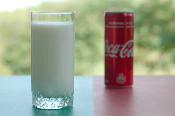 Кока-кола красная жестянка и чашка свежего молока на цветной поверхности — стоковое фото