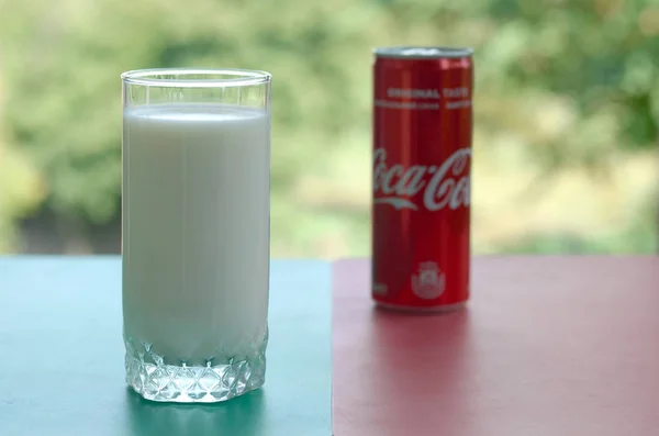 Plechovka od Coca-Coly a šálek čerstvého mléka na barevném povrchu — Stock fotografie