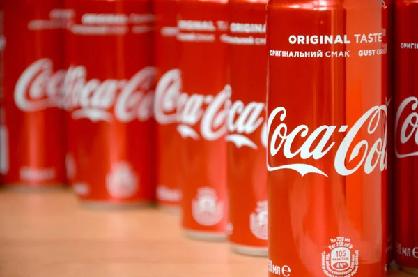 Логотип Coca-Cola напечатан на алюминиевых банках и размещен на столе торгового центра — стоковое фото