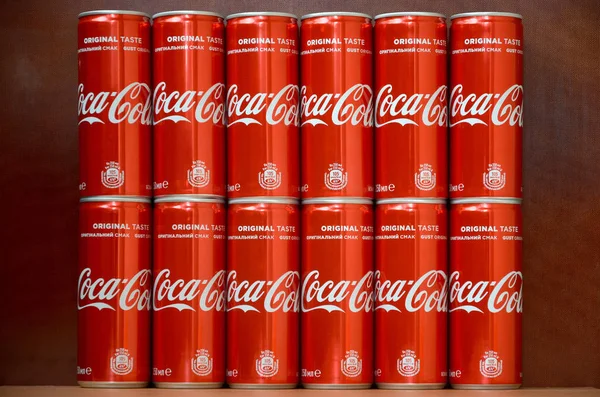 Логотип Coca-Cola напечатан на алюминиевых банках и размещен на столе торгового центра — стоковое фото