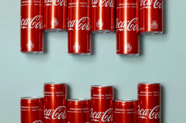 Flat lay shot carbonated red drink tin cans Coca Cola laying on pastel blue background — Stock Photo, Image