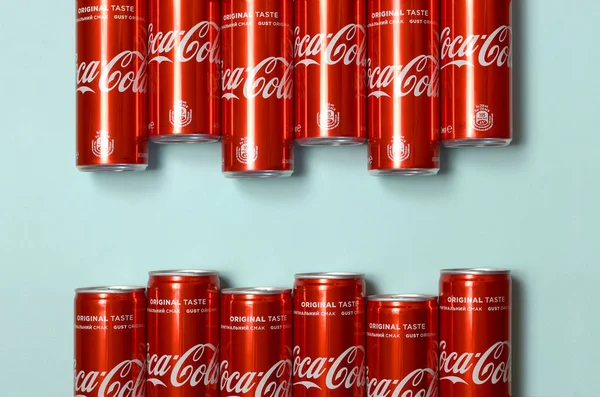 Flat lay shot carbonatadas latas de lata bebida roja Coca Cola puesta sobre fondo azul pastel — Foto de Stock