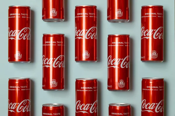 Flat lay shot carbonatadas latas de lata bebida roja Coca Cola puesta sobre fondo azul pastel — Foto de Stock
