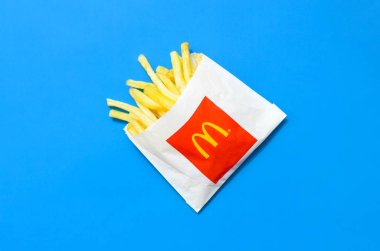 Parlak mavi arka plan üzerinde küçük paperbag Mcdonald's Patates kızartması