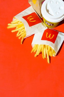Parlak kırmızı arka plan üzerinde küçük paperbag ve kahve fincanı Mcdonald's Patates kızartması