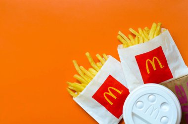 Parlak turuncu arka plan üzerinde küçük paperbag ve kahve fincanı Mcdonald's Patates kızartması