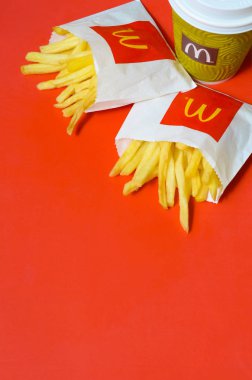 Parlak kırmızı arka plan üzerinde küçük paperbag ve kahve fincanı Mcdonald's Patates kızartması