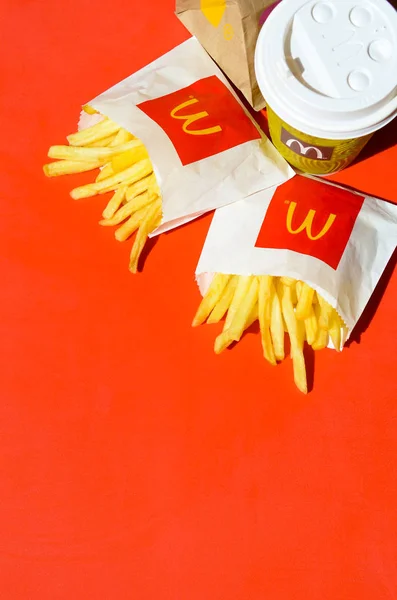 Patatas fritas McDonald 's en una pequeña bolsa de papel y una taza de café sobre fondo rojo brillante —  Fotos de Stock