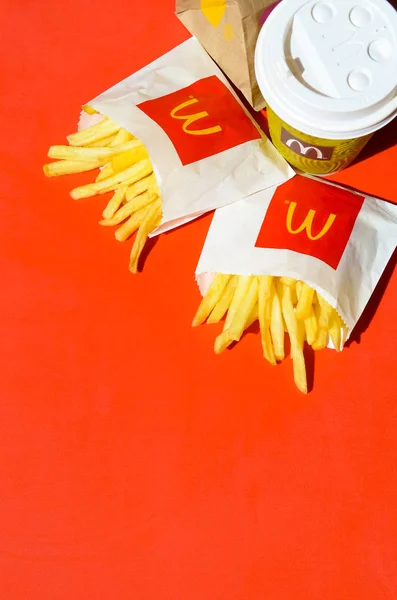 McDonald's French fries in small paperbag and coffee cup on bright red background — Stock Photo, Image