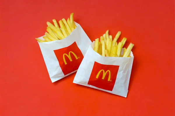 Batatas fritas McDonald 's em pequeno saco de papel sobre fundo vermelho brilhante — Fotografia de Stock