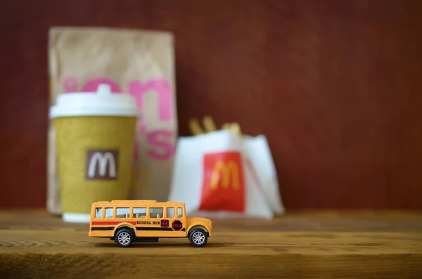 Mały autobus szkolny i Fast food Mcdonald's na drewnianym stole — Zdjęcie stockowe