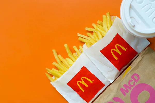 Patatas fritas McDonald 's en una pequeña bolsa de papel y una taza de café sobre fondo naranja brillante —  Fotos de Stock