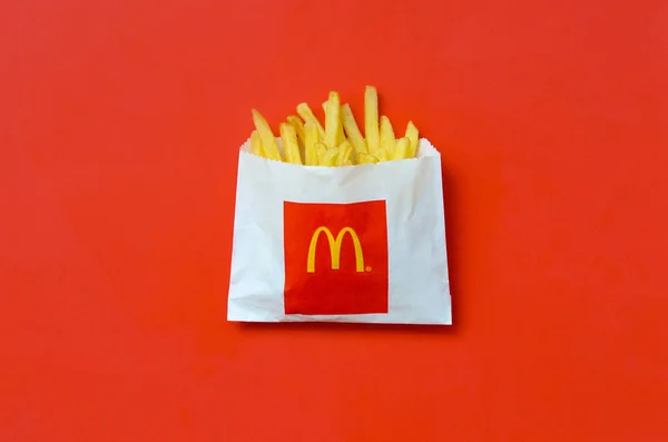 Pommes frites von mcdonald in kleiner Papiertüte auf leuchtend rotem Hintergrund — Stockfoto